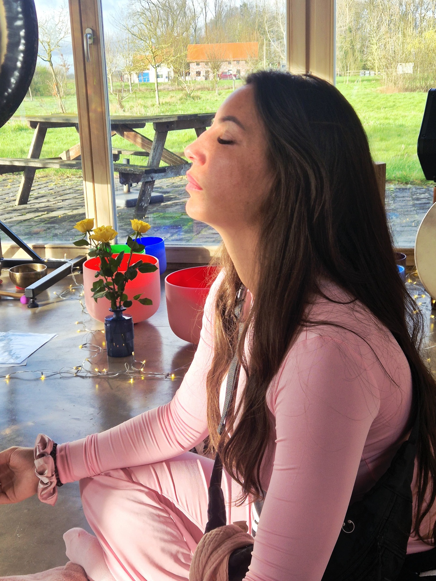 Participante en méditation devant les bols de cristal colorés face à la prairie, retraite d'été 2026
