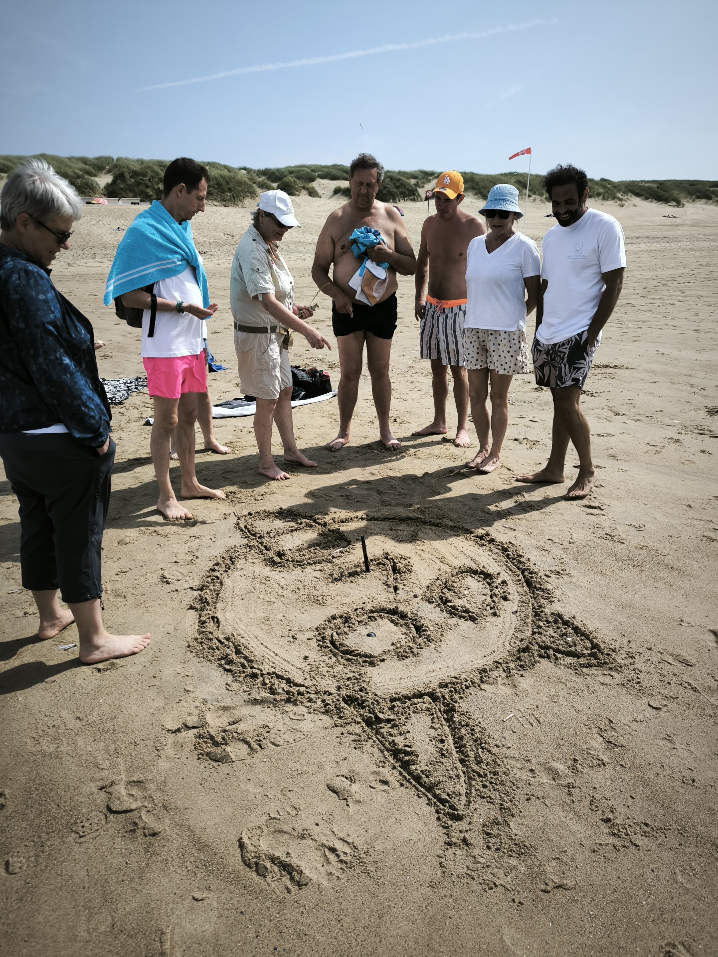 Mandala dessiné dans le sable sur la plage de la côte belge, retraite d'été 2026