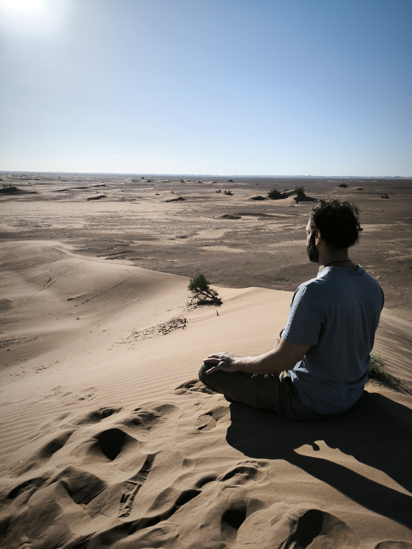 Nassim Khabazi en méditation sur une dune face au désert, voyage été 2026